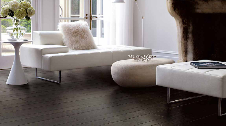 dark stained hardwood flooring in a modern minimalist living room with a wood fireplace and white couch